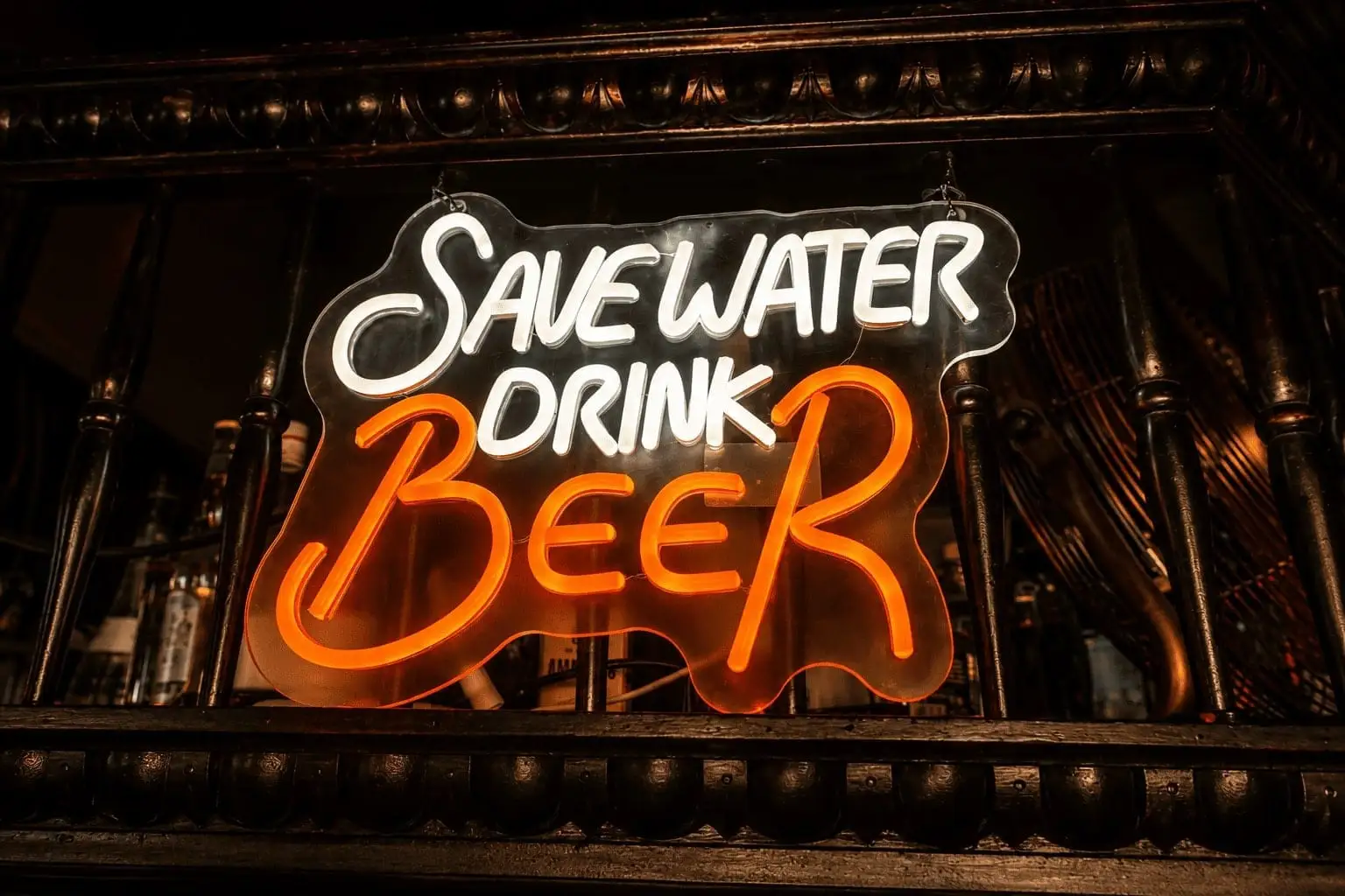 Neon-Schild „Save Water Drink Beer“ an der Bar